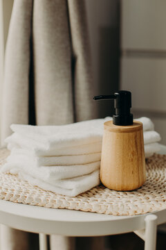 Minimalist still life of luxury spa essentials. White cotton towels with visible textured and wooden bottle with oil.