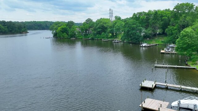 Aerial footage circling the lagoon's shoreline in front of some country houses, with an overcast sky and power lines