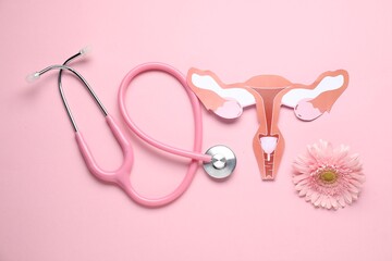 Fototapeta premium Gynecology. Female reproductive system made of paper, gerbera flower and stethoscope on pink background, flat lay