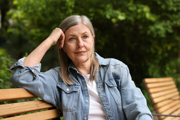 Fototapeta premium Beautiful senior woman sitting on bench in spring park