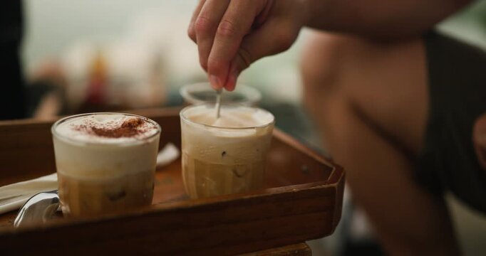 Enjoying the unique flavors of Vietnam's salted coffee, a traditional beverage with a delightful creamy top, being gently stirred on a wooden tray.