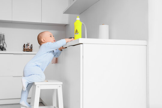 Curious baby reaching for poisonous cleaning product bottle on kitchen countertop, child safety hazard, critical importance of child safety and hazard prevention in the home environment