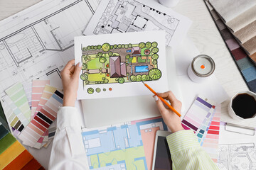 Landscape architect designing residential garden plan with color palette and blueprints on white desk © Pixel-Shot