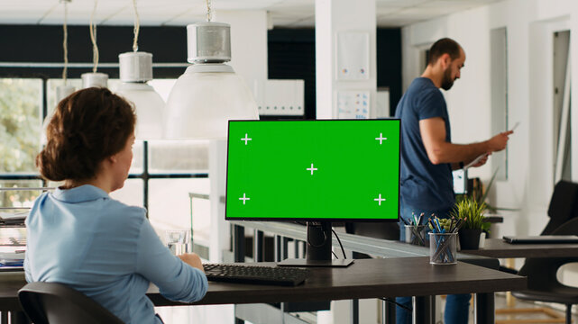 Operator of enterprise relying on chroma key isolated green screen display. Company executive using computer at startup workplace while examining mockup template.
