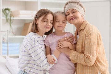 Fototapeta premium Little girl with her mother and granny after chemotherapy hugging in clinic