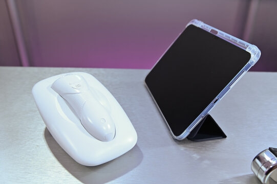 handheld diagnostic device on its charging cradle alongside a digital tablet supported by a black magnetic stand case