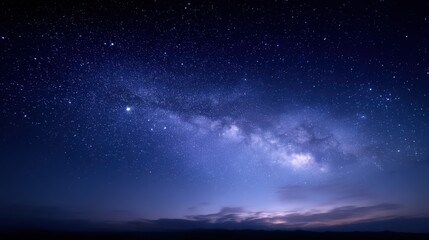 Fototapeta premium Vast Milky Way Galaxy stretching across the deep blue night sky filled with countless stars and faint clouds