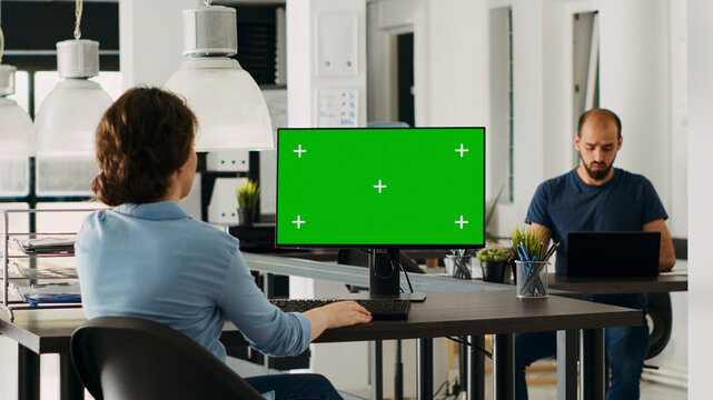 Employee using computer at desk, monitor running green screen template in business agency office. Company specialist looking at isolated chroma key display with mockup copy space, digital network.