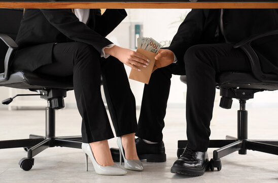 Business people exchanging money under table, bribery and corruption in corporate dealings, financial crime and illicit transactions