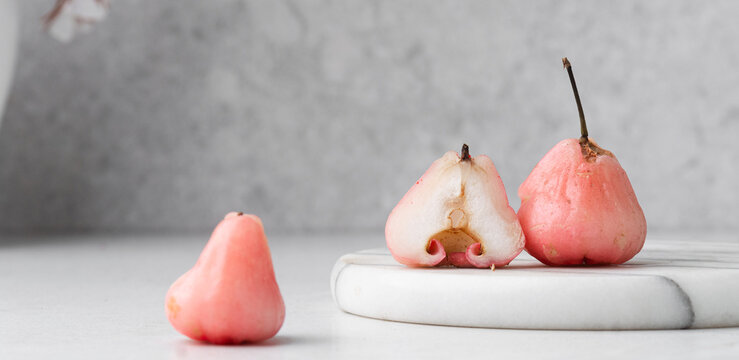 Light pink rose apples on a white marble tray, closeup view of rose wax apples on textured white background
