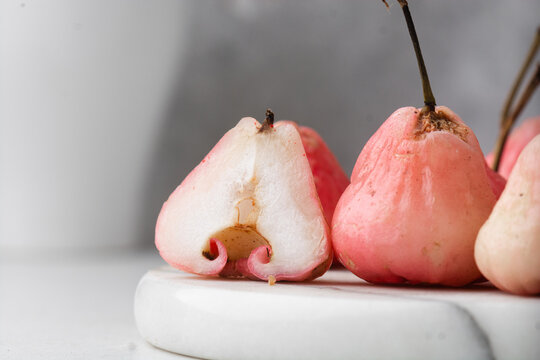 Light pink rose apples on a white marble tray, closeup view of rose wax apples on textured white background