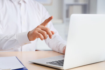 Fototapeta premium Businessman hand pointing at laptop screen during online presentation or virtual meeting in modern office, professional working environment, emphasizing digital communication and remote collaboration