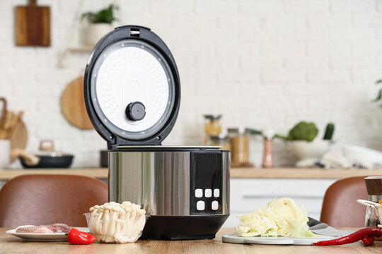 Modern electric rice cooker with open lid on kitchen countertop, fresh ingredients for healthy meal preparation