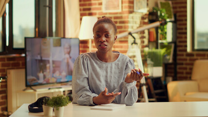 Fototapeta premium Freelancer waving on videocall, attending important online conference from home workstation. Woman using secured network connection to meet with contractor on telework chat. Tripod shot.