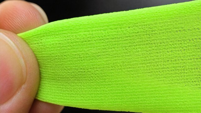 Extreme close-up of stretched fluorescent fabric showing knit structure.