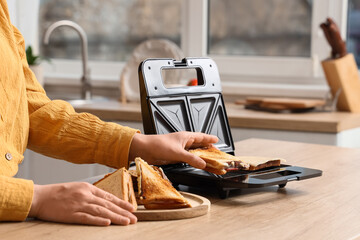 Person making grilled cheese sandwiches in a modern sandwich maker for quick breakfast or lunch...