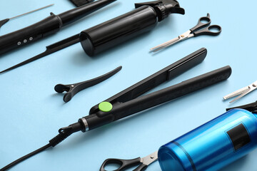 Fototapeta premium Professional hair styling tools and equipment for salon or home use flat iron scissors combs and spray bottles on blue background