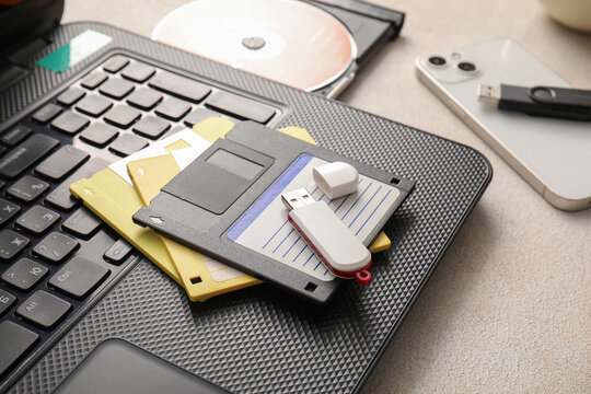 Digital data storage evolution: floppy disks, USB flash drive, CD-ROM, smartphone, and laptop keyboard