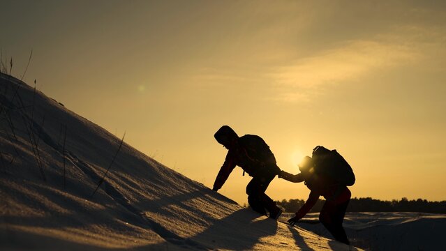 Teamwork people hiker climb hill. Silhouette group of climbers, hikers lends helping hand while climbing snowy mountain. Work in team of businessmen, help in overcoming business difficulties, problems
