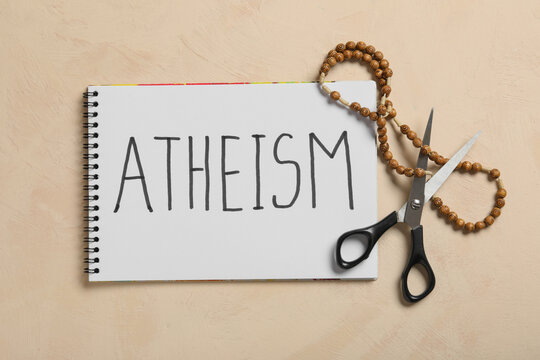 Atheism with notebook, scissors, and rosary beads on textured background, religious freedom and belief
