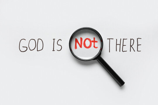 Magnifying glass over "not" in "god is not there" text, atheism and doubt concept, religious skepticism