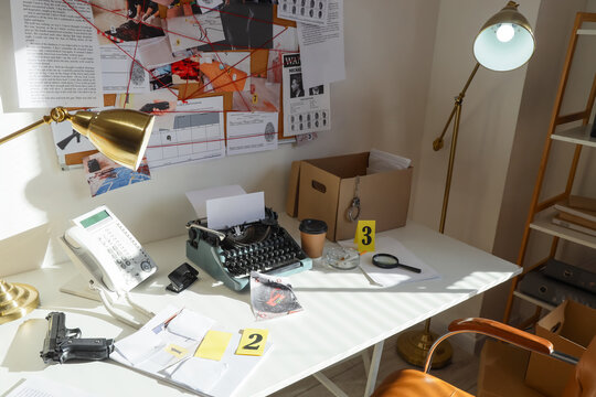 Detective investigation board with evidence, typewriter, and crime scene tools on a desk, mystery and forensic research