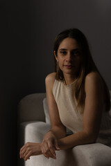 Obraz premium Young woman sitting on sofa looking at camera indoors