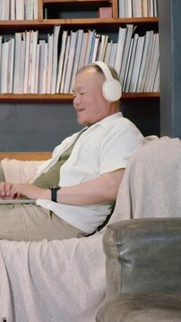 Vertical video: Hearing ping, senior in white headset typing on laptop at home, checking messages