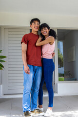 Naklejka premium Diverse couple standing close on tiled porch in front of slatted door showing smartwatch