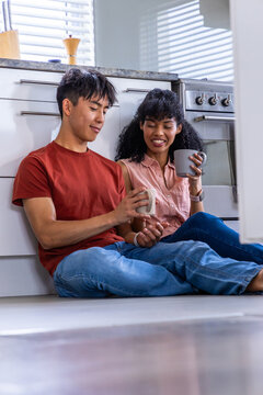 Vertical video: Couple sitting on kitchen floor, blinds sparking motion icons on mugs for home ads