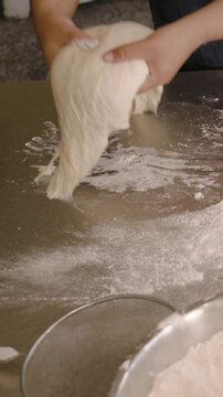 Vertical video: Hand entering dusting flour chef hands shaping dough to bake in kitchen apron