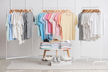 Fototapeta premium Retail clothing display with assorted t-shirts on racks, folded stacks, and sneakers for fashion merchandising