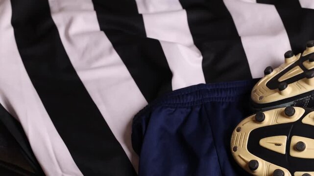 soccer ball and cleats on striped jersey (association football kit with shorts and boots) sports player gear competition playing play goal scoring
