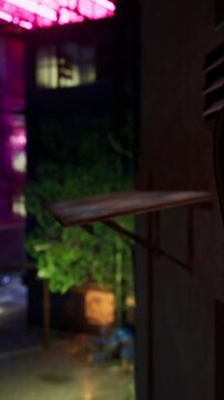 A mailbox stands empty beside a wooden shelf. The area is dimly lit with neon lights in the background. Green plants surround the scene, creating an urban atmosphere at night.