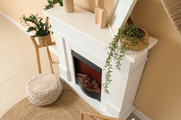 Obraz premium Fireplace, pouf and houseplants in interior of living room