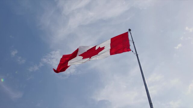 The Canadian flag flies high above downtown Halifax. The sky is blue as the flag flaps in the wind. This spot shows a symbol of Canada pride in the city