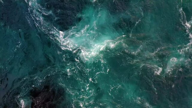 A mesmerizing aerial view of powerful turquoise ocean current creating intricate patterns and whirlpools in the water motion background footage.
