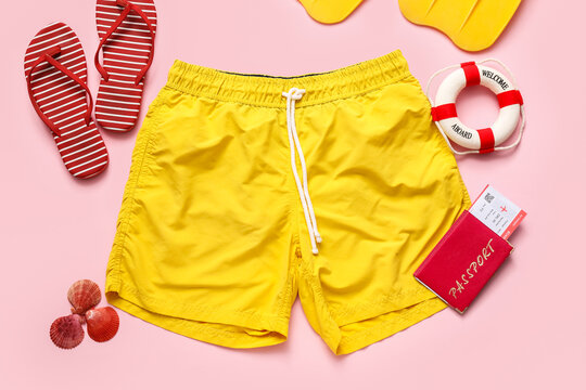 Summer travel vacation planning flat lay with yellow swim trunks, red flip-flops, passport, and beach accessories