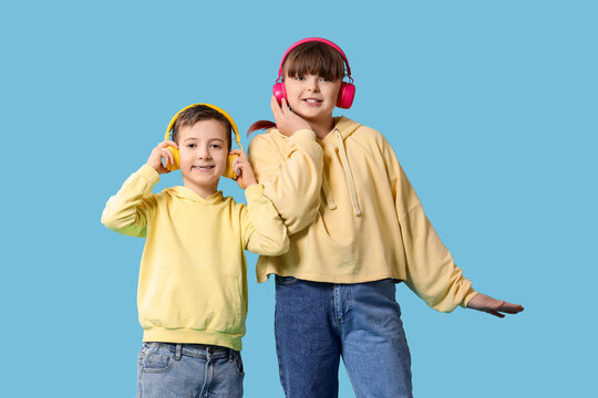 Cute girl with her brother in headphones on blue background