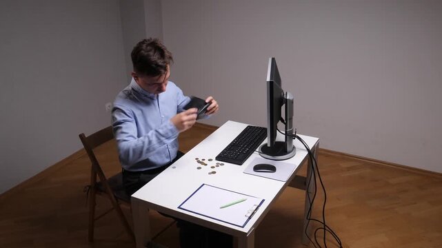 Man sitting at desk counting a few coins from an empty wallet, overhead view conveying financial struggle, budgeting, debt stress, and careful personal finance planning