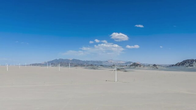 Aerial Time-lapse of Vast Desert Wind Farm with Turbines Against Blue Sky and Distant Mountains  