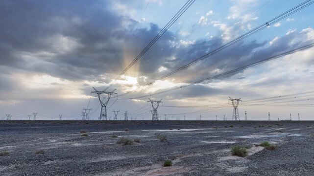 Time-lapse of the high-voltage transmission towers on Gobi desert at dusk with crepuscular rays
