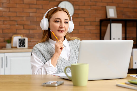 Focused woman in headphones working remotely on laptop, online learning and business communication