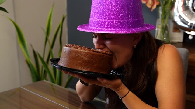 Joyful birthday woman greedily eating chocolate cake