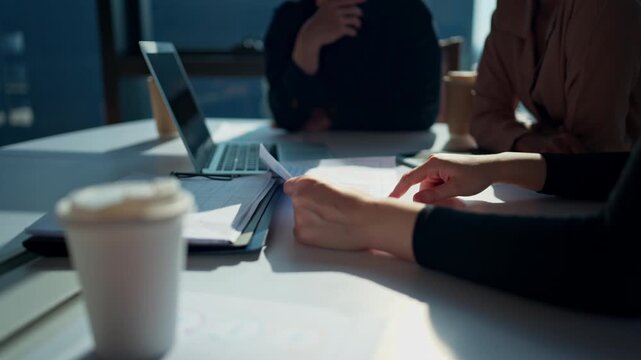 Business professionals use hand gestures to illustrate the analysis of business and financial strategies through documents and computer presentations