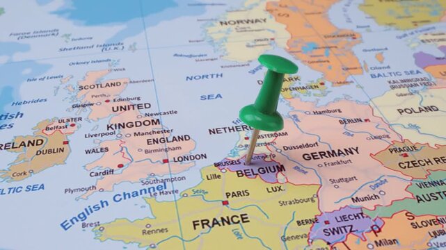 A green pushpin marks the location of belgium on a colorful political map of europe, slow motion footage.