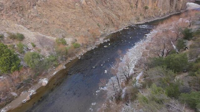 R&iacute;o Percy flows through a rocky gorge near Trevelin, Chubut, Argentina, passing beneath a bridge amid Patagonian steppe vegetation and exposed bedrock formations, FPV forward flythrough shot.