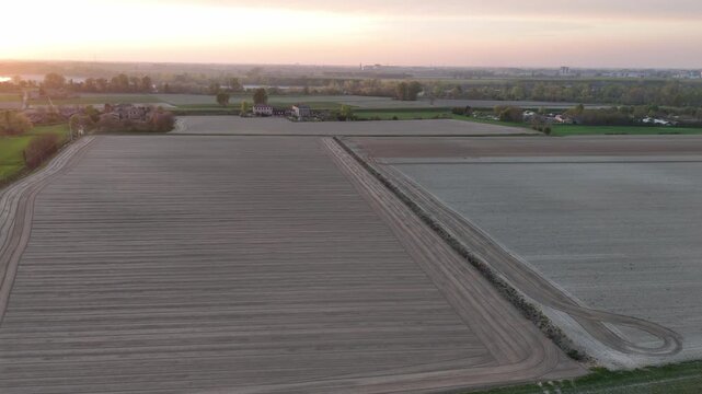 Prepared agricultural fields stretch across the Po Valley in Emilia-Romagna, Italy, revealing intensive farming, cultivated soil and geometric land patterns under warm sunset light drone lateral slide