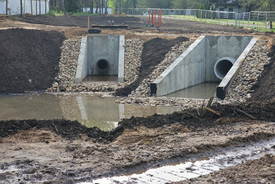 Construction site shows drainage pipes being placed next to a waterlogged