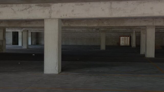 Steady left to right pan revealing empty concrete parking structure with support columns.